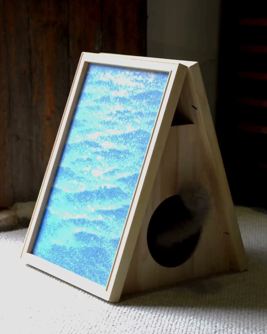 The Canvas House, a pine A-frame wearing a framed wave canvas, with a round doorway